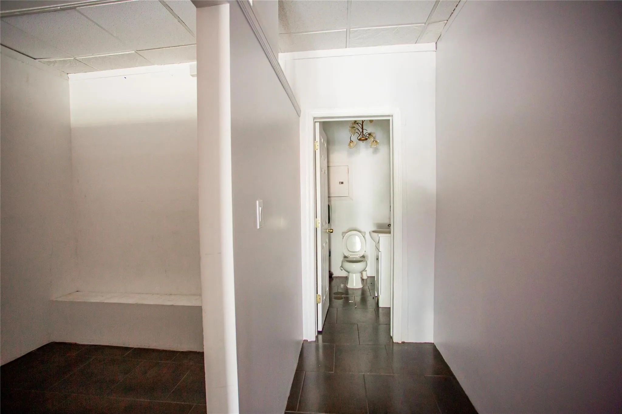 Hall featuring a drop ceiling and dark tile patterned flooring Hall featuring a drop ceiling and dark tile patterned flooring