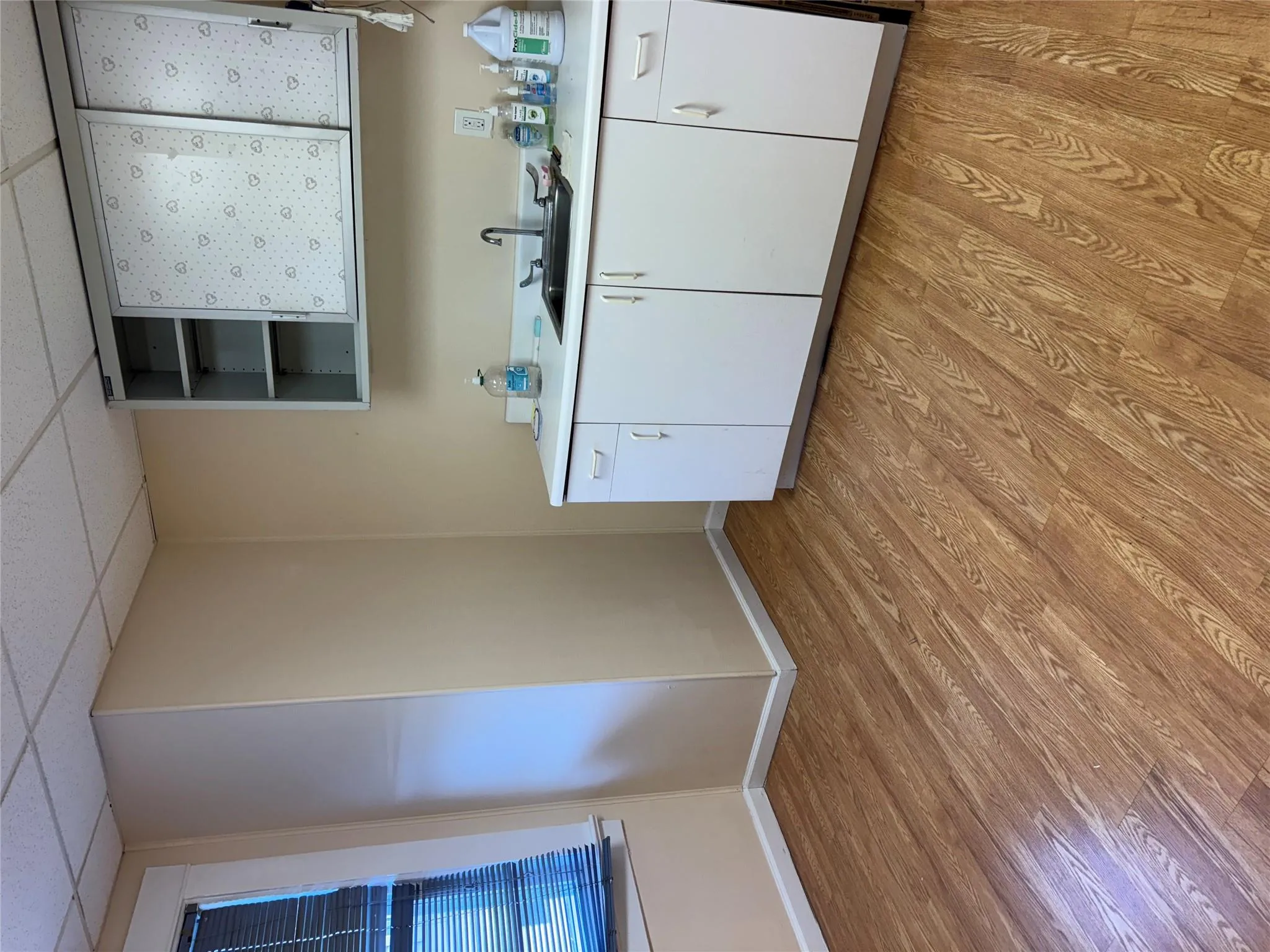 Kitchen with a sink, a drop ceiling, open shelves, light countertops, and light wood-style floors Kitchen with a sink, a drop ceiling, open shelves, light countertops, and light wood-style floors