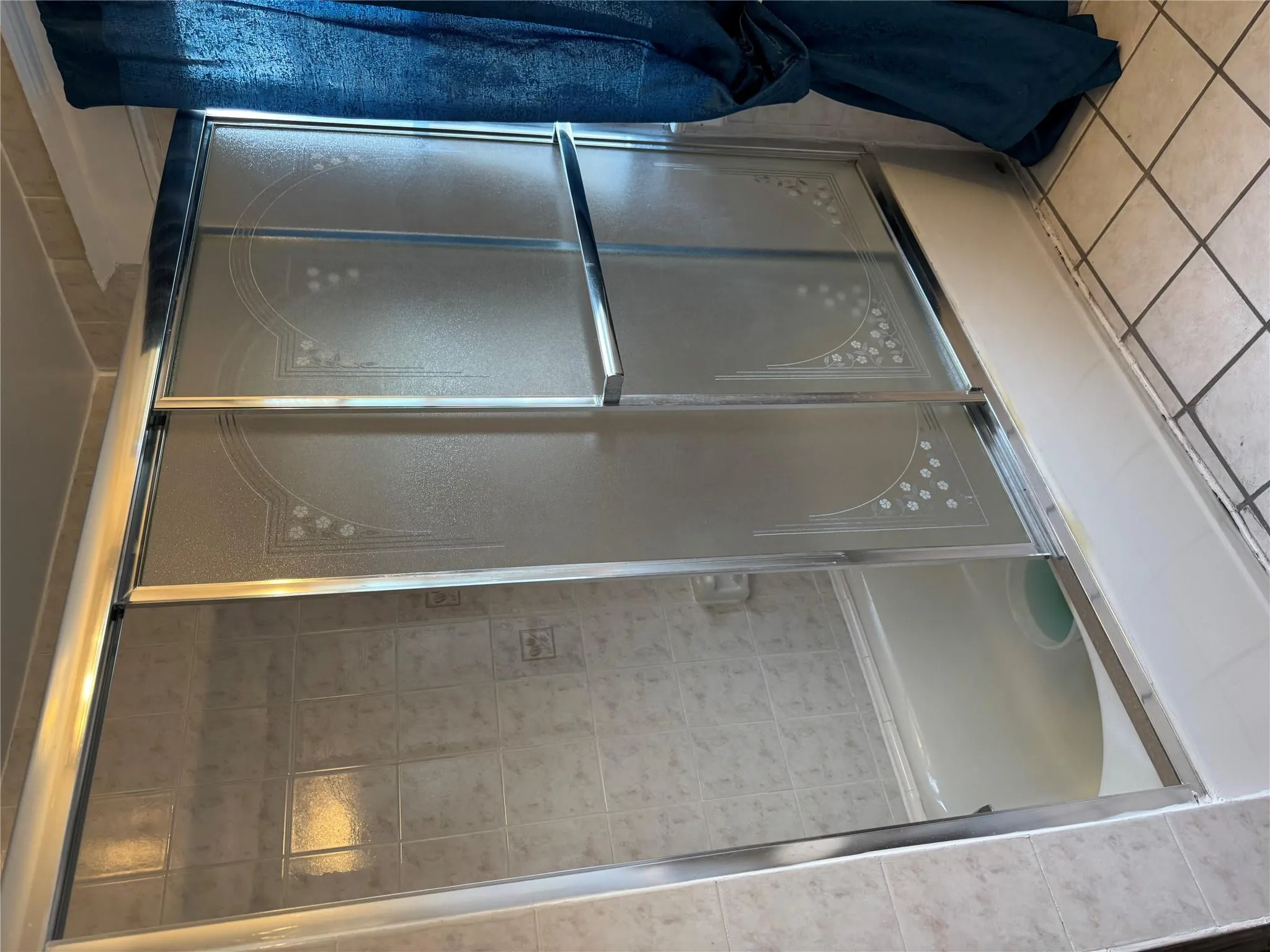 Bathroom with bath / shower combo with glass door and tile patterned floors Bathroom with bath / shower combo with glass door and tile patterned floors