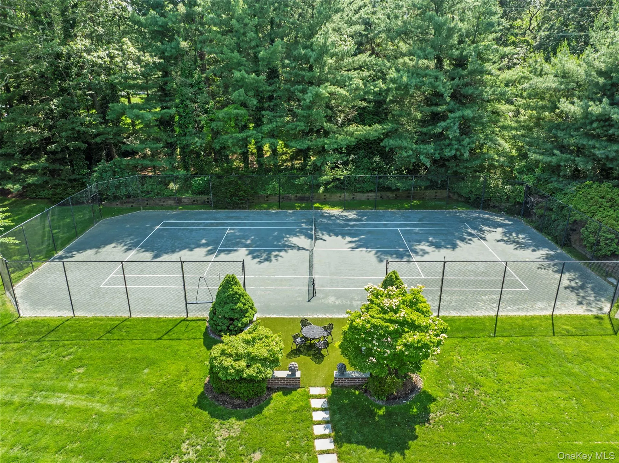 View of tennis court located behind sweeping green lawns & pool View of tennis court located behind sweeping green lawns & pool