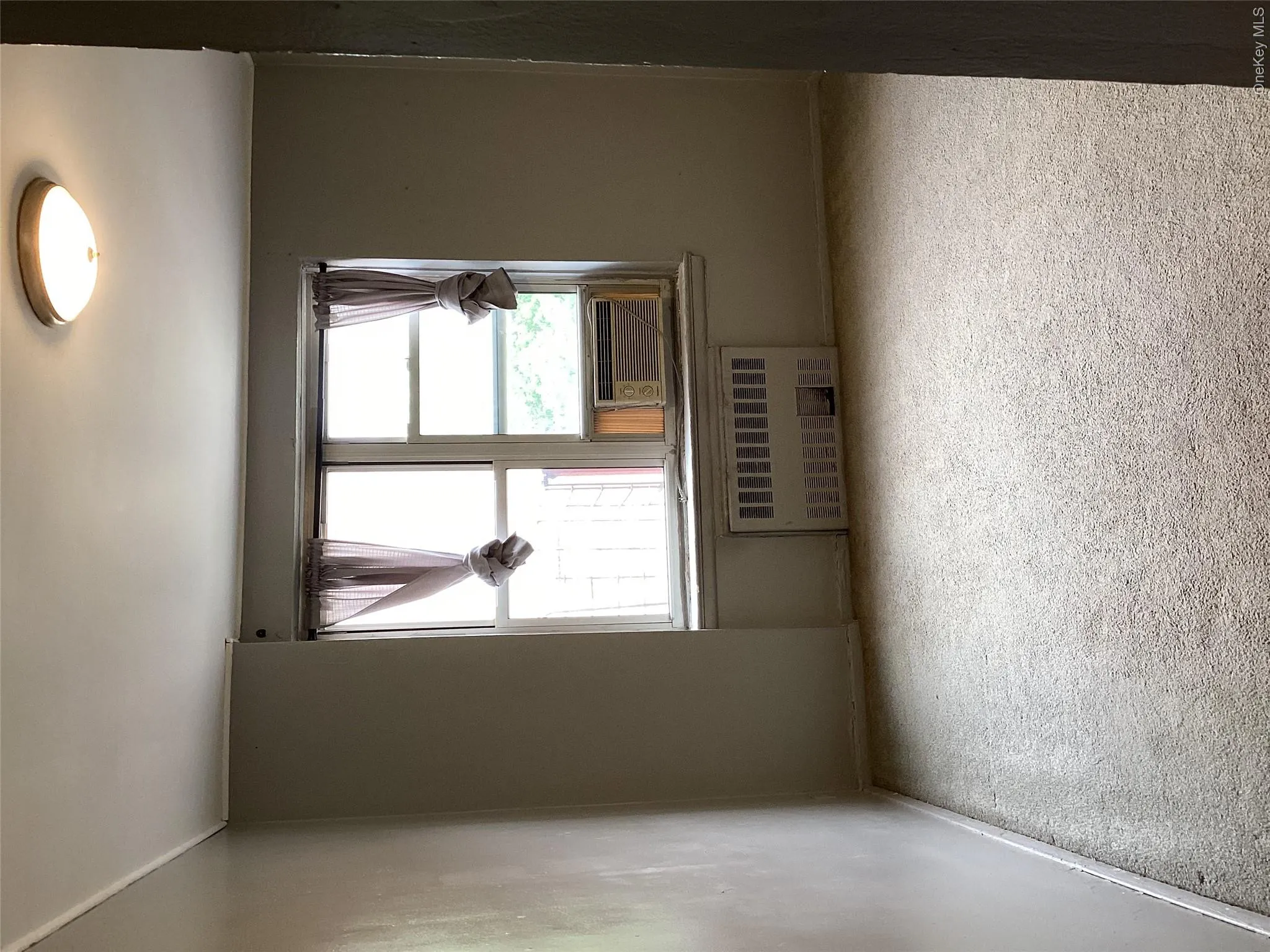 Carpeted empty room featuring radiator heating unit, baseboards, and cooling unit Carpeted empty room featuring radiator heating unit, baseboards, and cooling unit