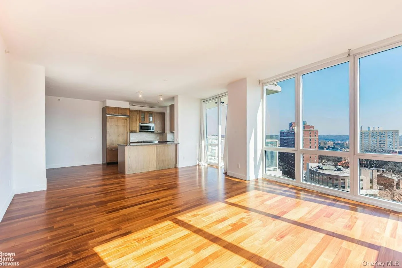 Unfurnished living room featuring dark wood-style flooring, expansive windows, a view of city, and baseboards Unfurnished living room featuring dark wood-style flooring, expansive windows, a view of city, and baseboards