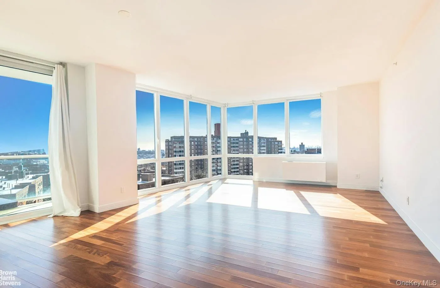 Spare room featuring a view of city, hardwood / wood-style floors, floor to ceiling windows, and baseboards Spare room featuring a view of city, hardwood / wood-style floors, floor to ceiling windows, and baseboards