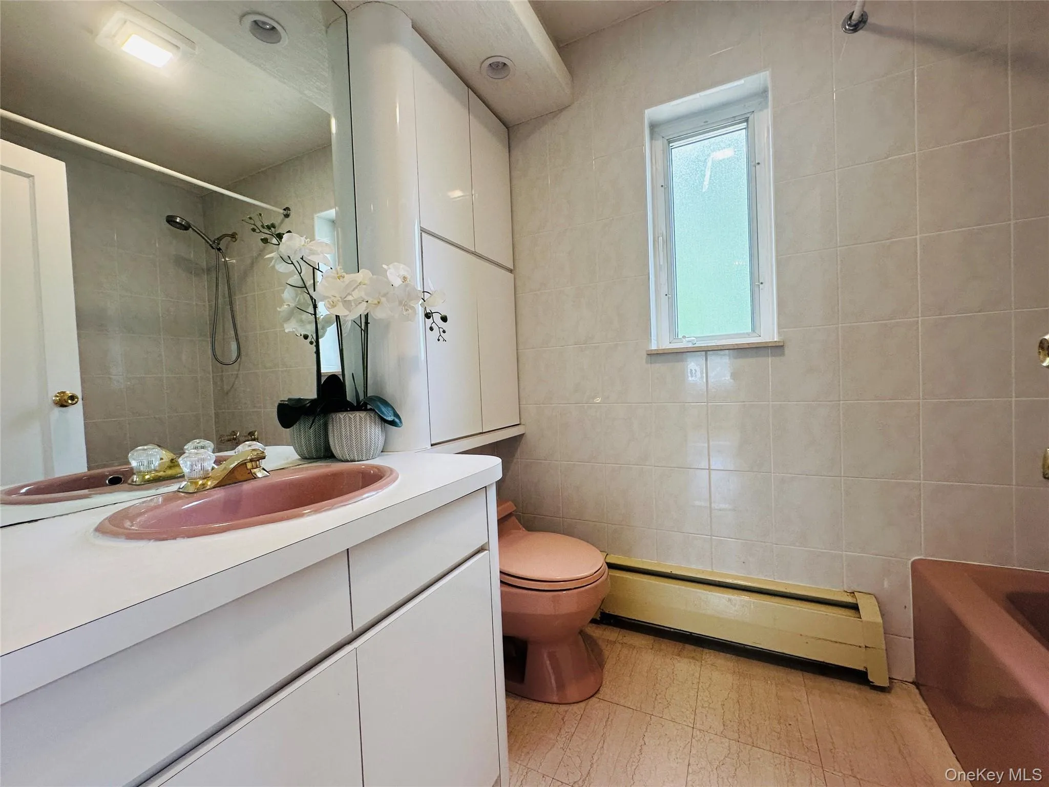 Bathroom featuring a baseboard radiator, vanity, tile walls, and shower / bath combination Bathroom featuring a baseboard radiator, vanity, tile walls, and shower / bath combination