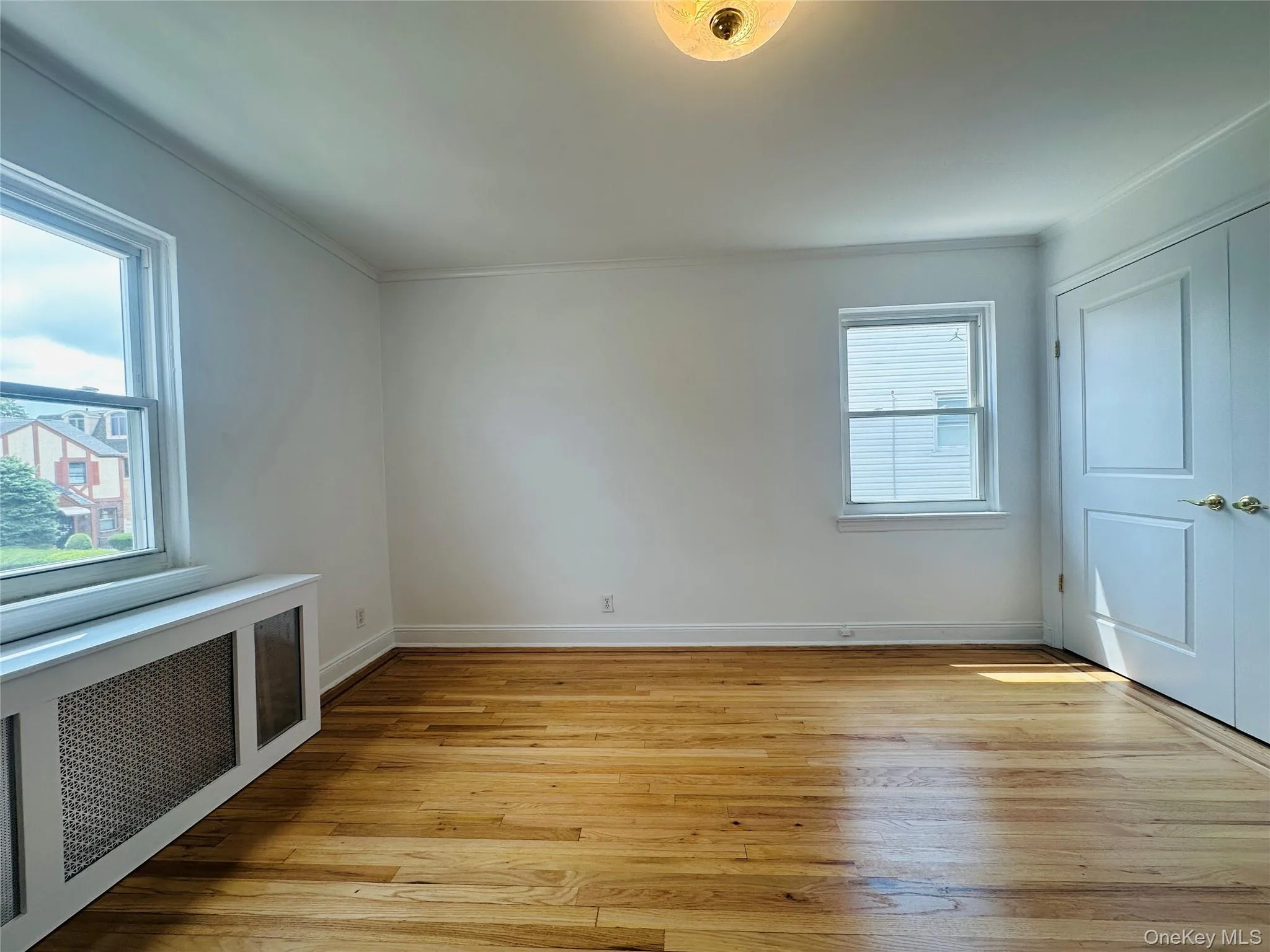 Empty room with radiator, light wood finished floors, and crown molding Empty room with radiator, light wood finished floors, and crown molding