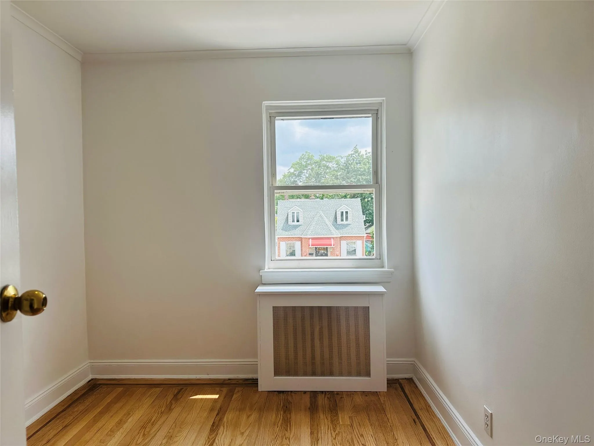 Spare room featuring radiator, wood finished floors, and crown molding Spare room featuring radiator, wood finished floors, and crown molding
