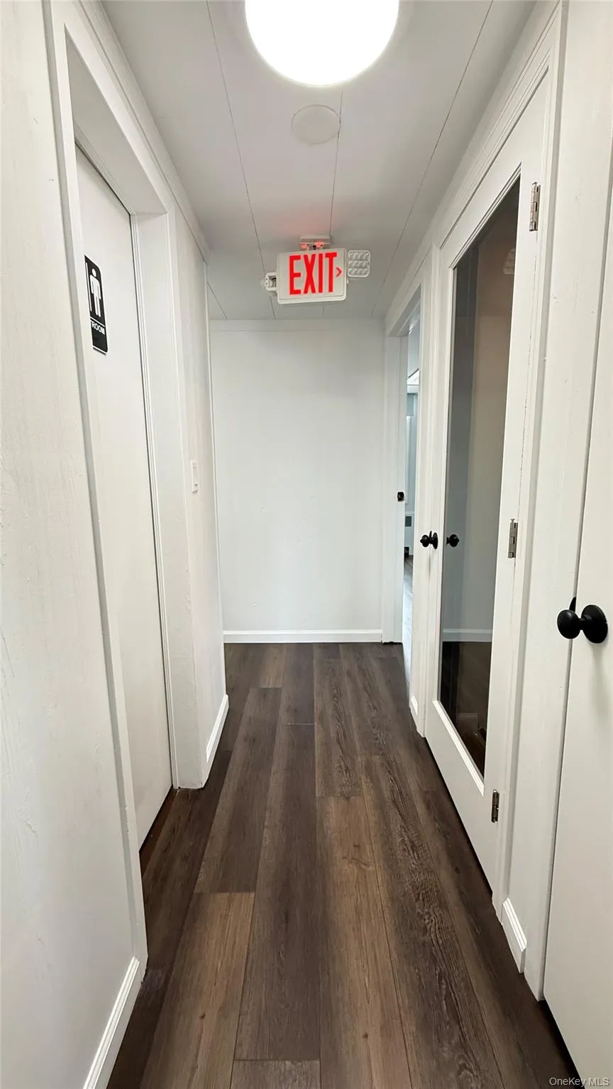 Hallway with dark wood-style flooring and baseboards Hallway with dark wood-style flooring and baseboards