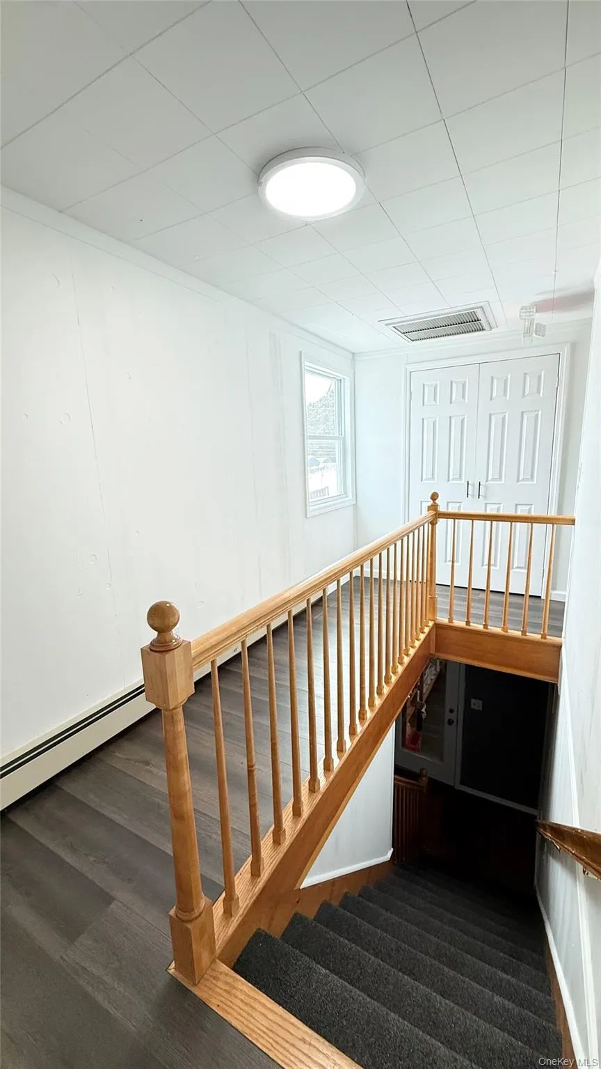 Stairs featuring a baseboard radiator and wood finished floors Stairs featuring a baseboard radiator and wood finished floors