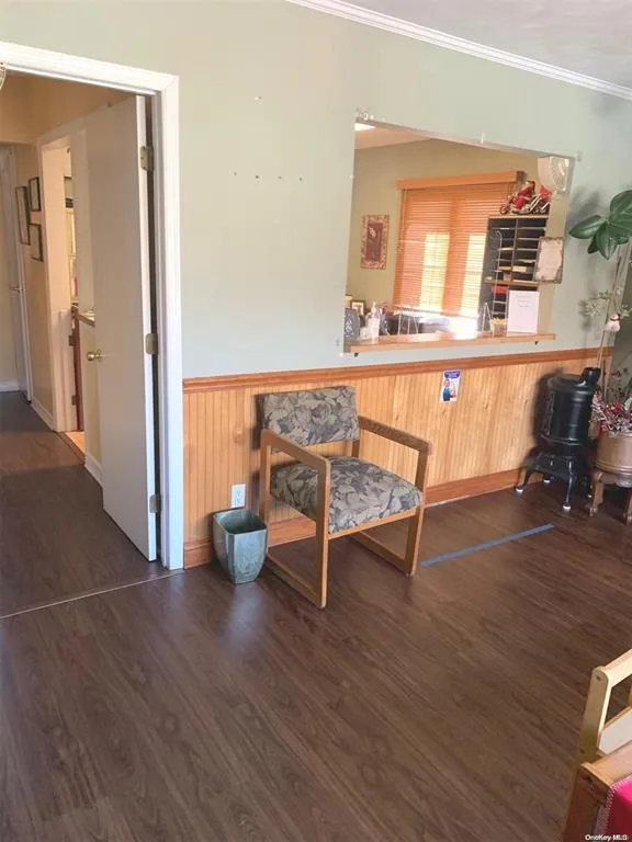 Sitting room with wainscoting, dark wood-type flooring, crown molding, and wooden walls Sitting room with wainscoting, dark wood-type flooring, crown molding, and wooden walls