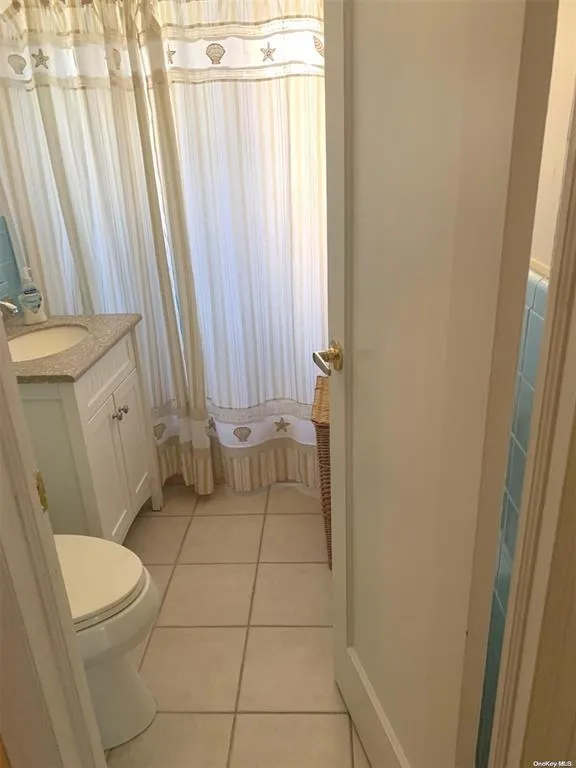 Bathroom featuring vanity, tile patterned floors, and toilet Bathroom featuring vanity, tile patterned floors, and toilet