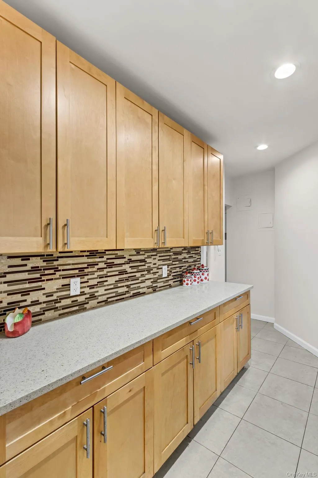 Kitchen with light brown cabinetry, backsplash, baseboards, light tile patterned flooring, and recessed lighting Kitchen with light brown cabinetry, backsplash, baseboards, light tile patterned flooring, and recessed lighting