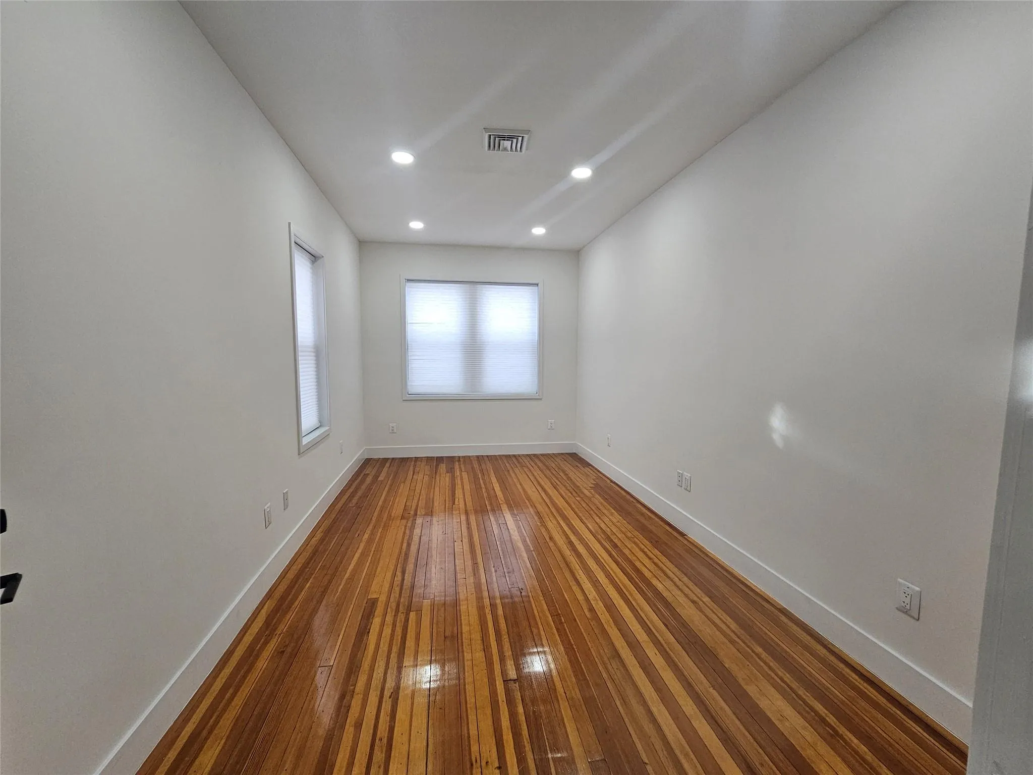 Empty room featuring wood-type flooring, baseboards, and recessed lighting Empty room featuring wood-type flooring, baseboards, and recessed lighting