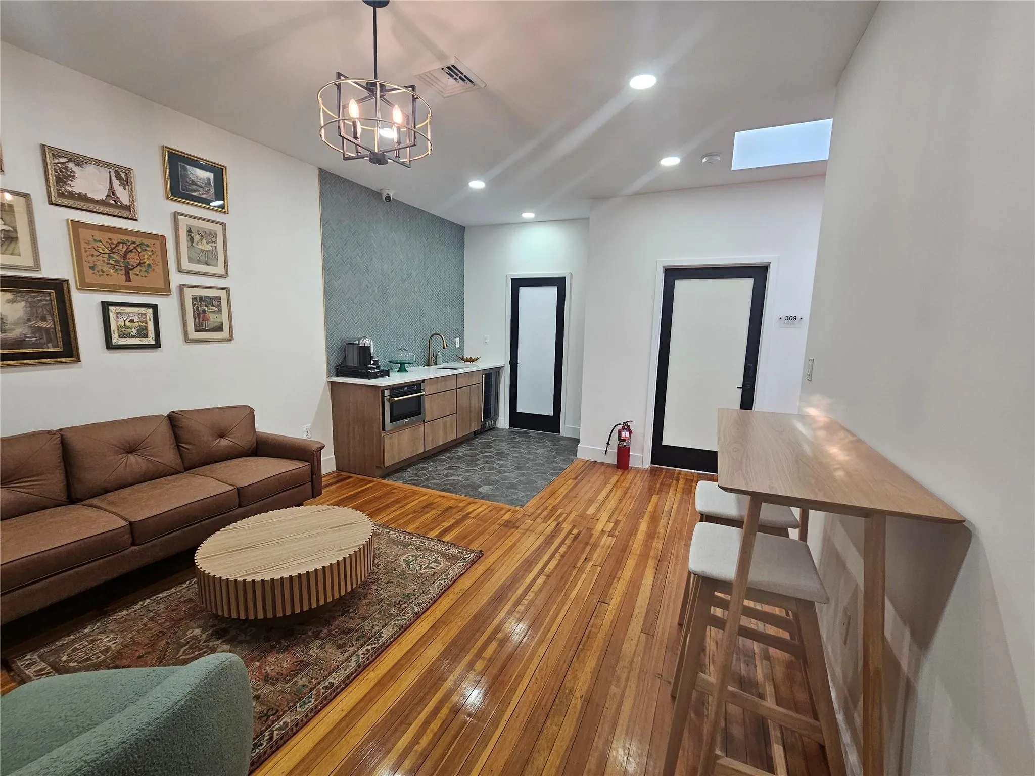 Living area with dark wood-style floors, recessed lighting, a chandelier, a skylight, and baseboards Living area with dark wood-style floors, recessed lighting, a chandelier, a skylight, and baseboards