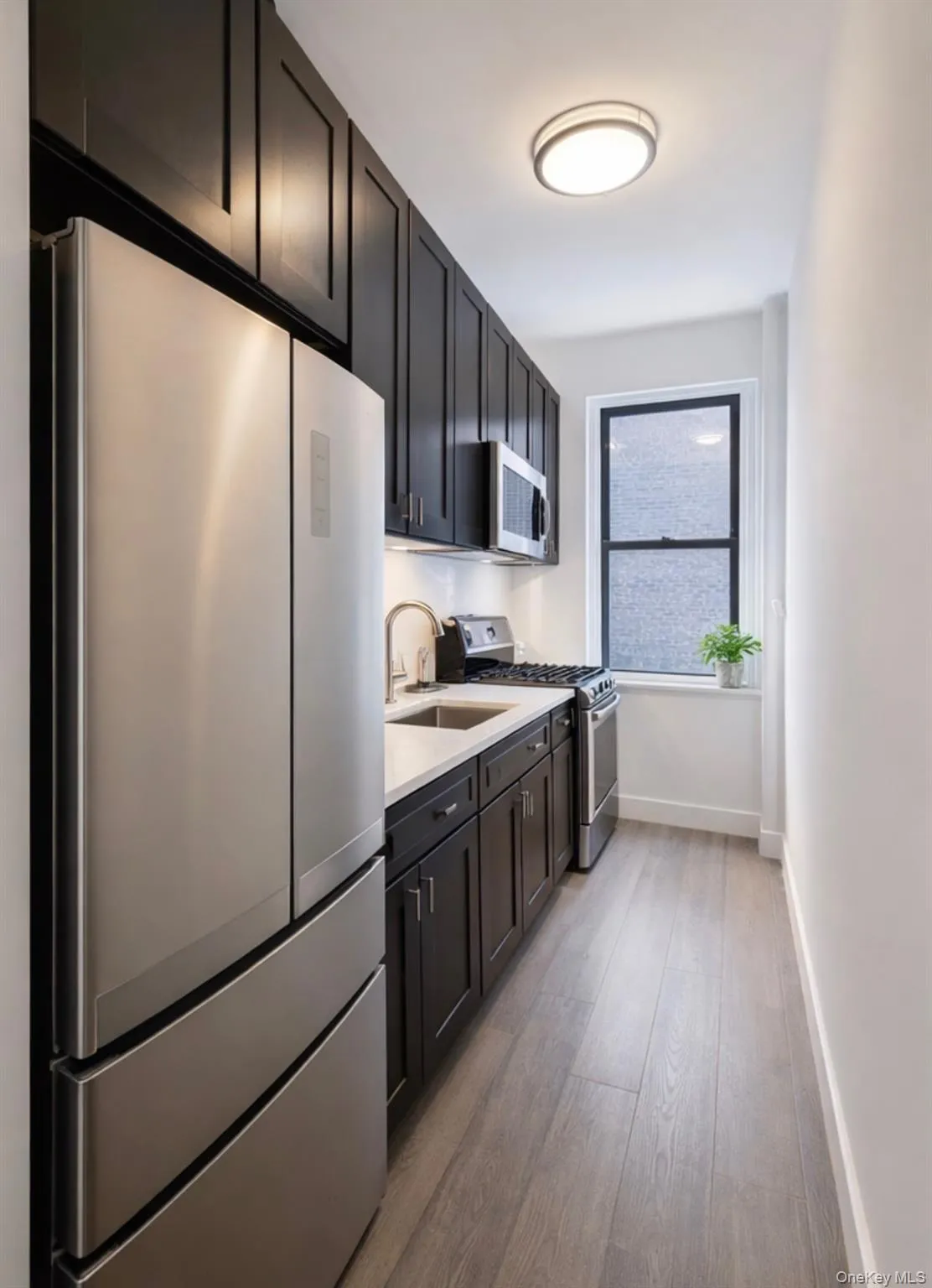 Kitchen featuring stainless steel appliances, light wood-style floors, and light stone countertops Kitchen featuring stainless steel appliances, light wood-style floors, and light stone countertops