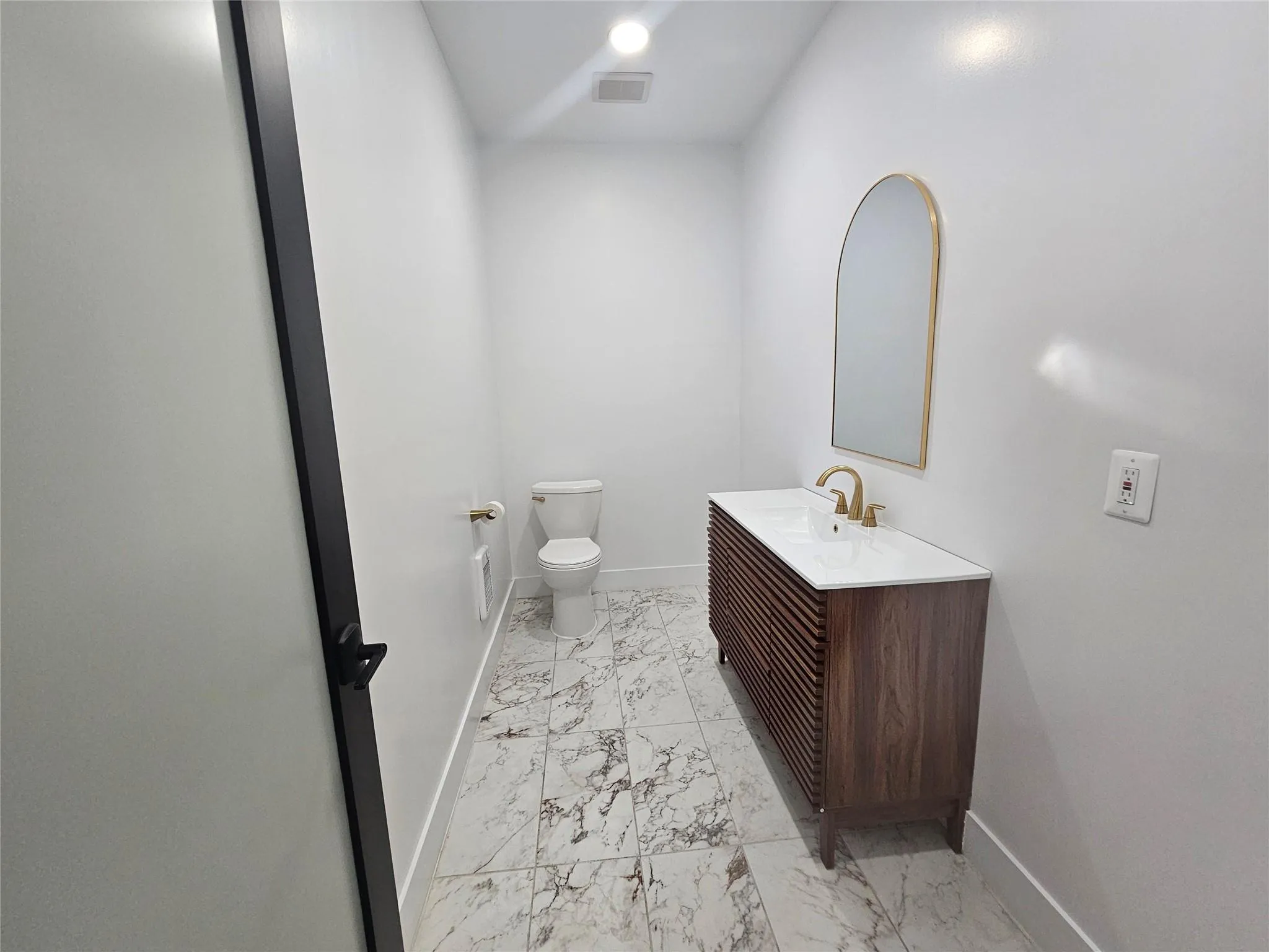 Bathroom featuring marble look tiles, baseboards, toilet, and vanity Bathroom featuring marble look tiles, baseboards, toilet, and vanity