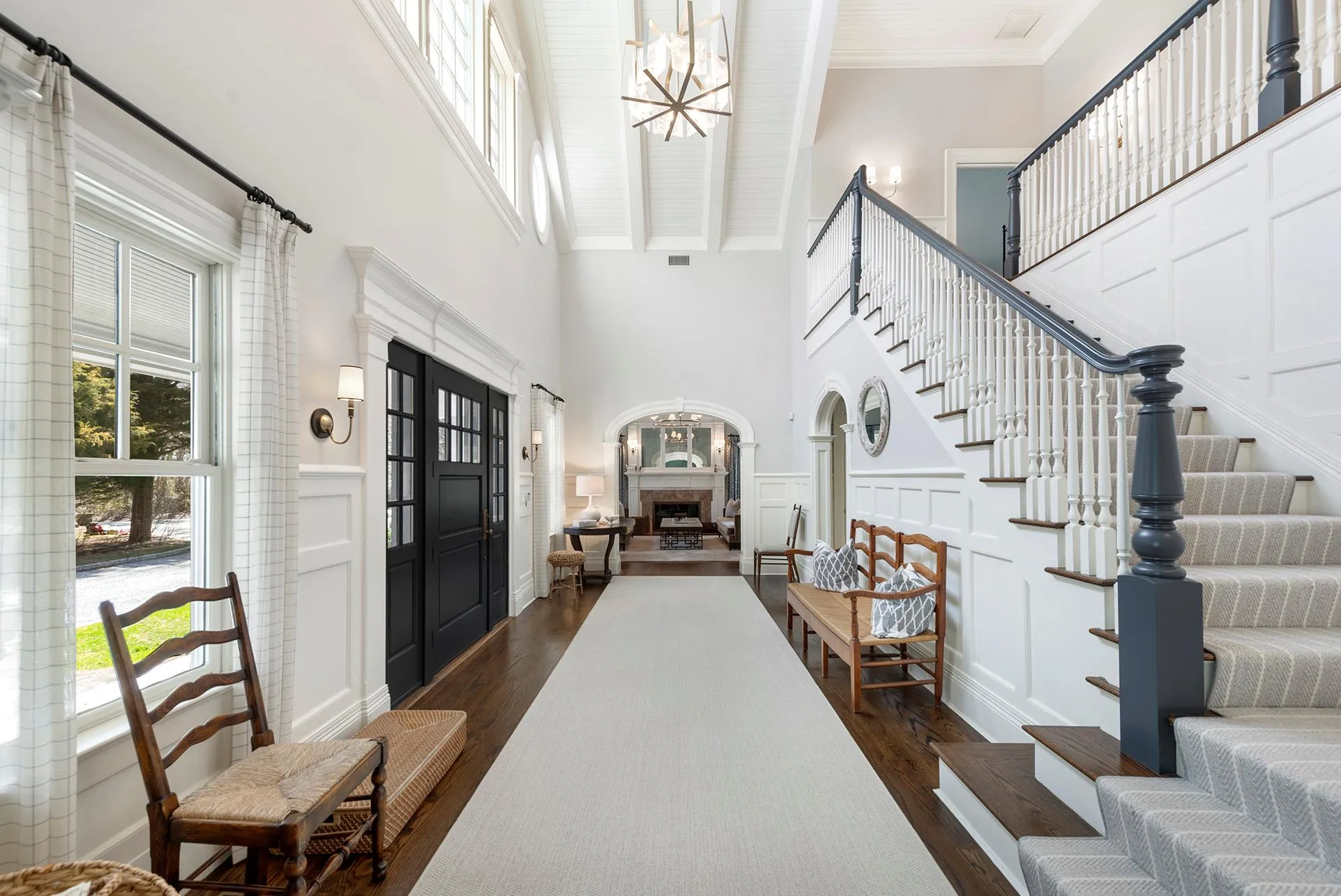 Foyer entrance with a high ceiling, a chandelier, dark wood-type flooring, healthy amount of natural light, and a decorative wall Foyer entrance with a high ceiling, a chandelier, dark wood-type flooring, healthy amount of natural light, and a decorative wall