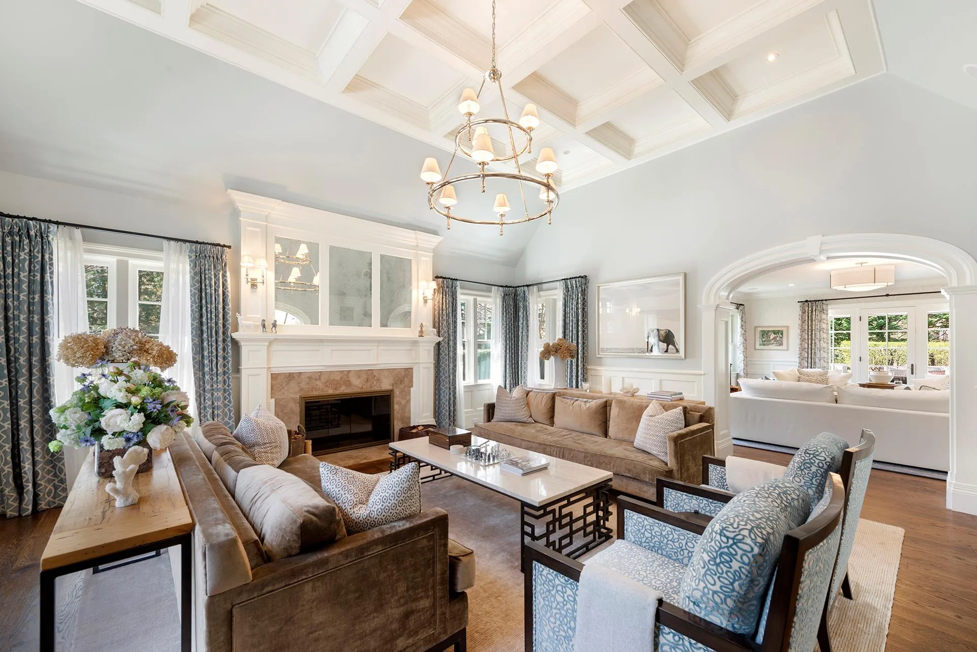 Living room featuring a tiled fireplace, wood finished floors, beam ceiling, coffered ceiling, and crown molding Living room featuring a tiled fireplace, wood finished floors, beam ceiling, coffered ceiling, and crown molding