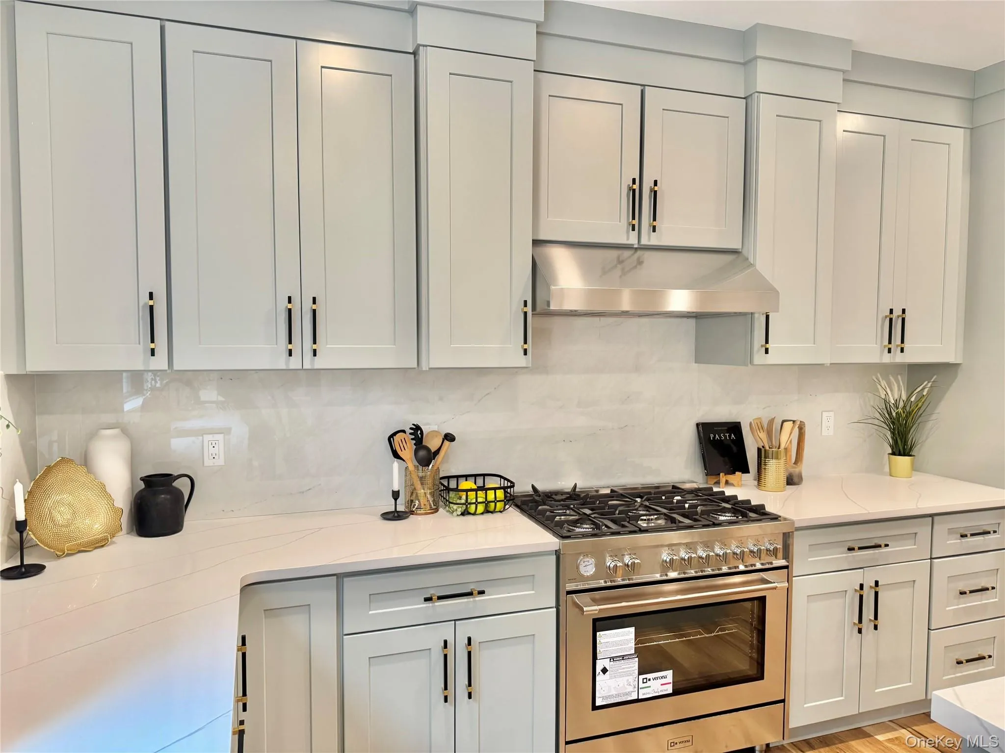 Kitchen featuring stainless steel gas range, under cabinet range hood, tasteful backsplash, and light stone counters Kitchen featuring stainless steel gas range, under cabinet range hood, tasteful backsplash, and light stone counters