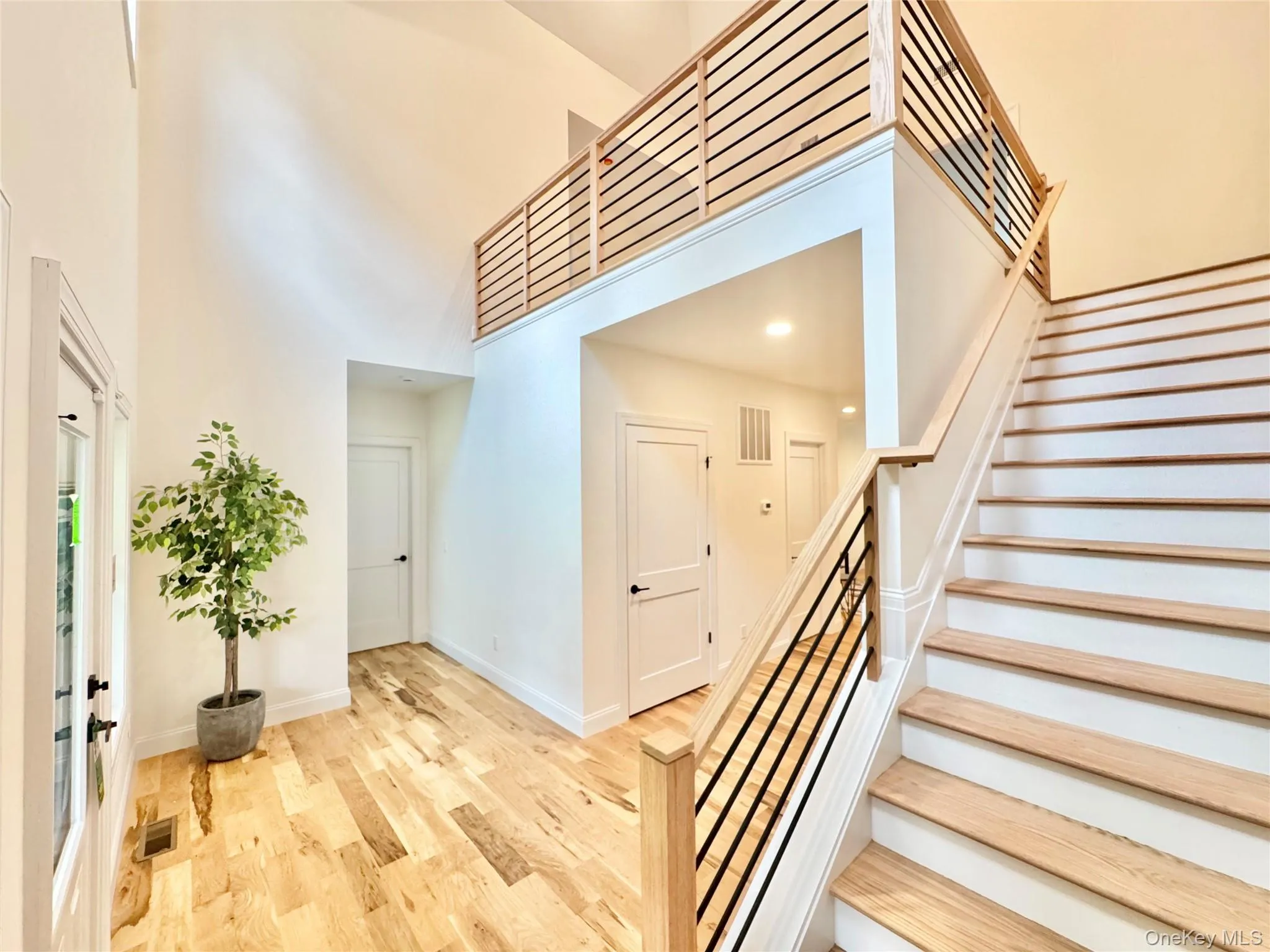 Stairway with a high ceiling, wood finished floors, and recessed lighting Stairway with a high ceiling, wood finished floors, and recessed lighting