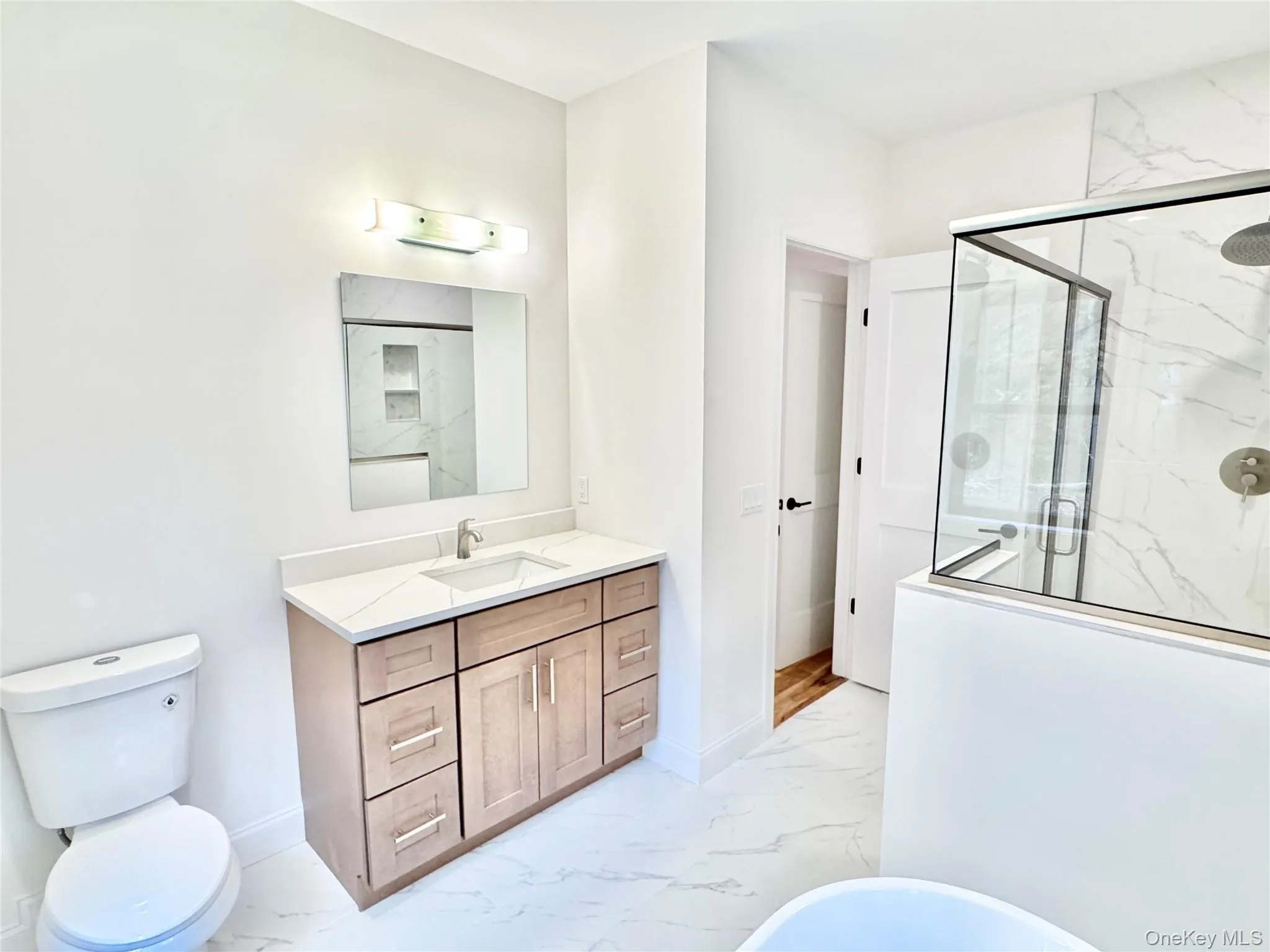 Bathroom featuring light marble finish flooring, a marble finish shower, vanity, and a freestanding tub Bathroom featuring light marble finish flooring, a marble finish shower, vanity, and a freestanding tub