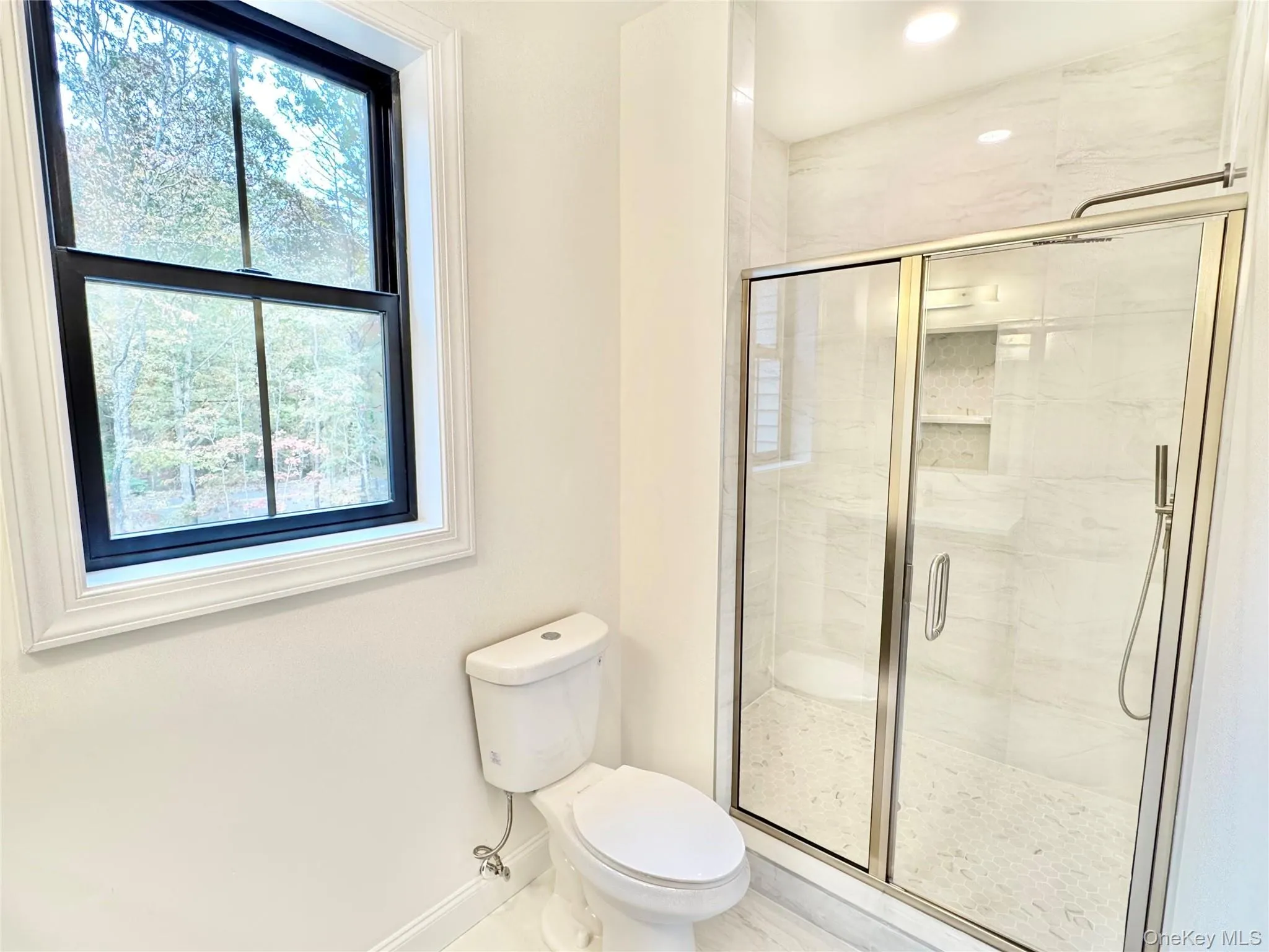 Bathroom featuring a shower stall and baseboards Bathroom featuring a shower stall and baseboards