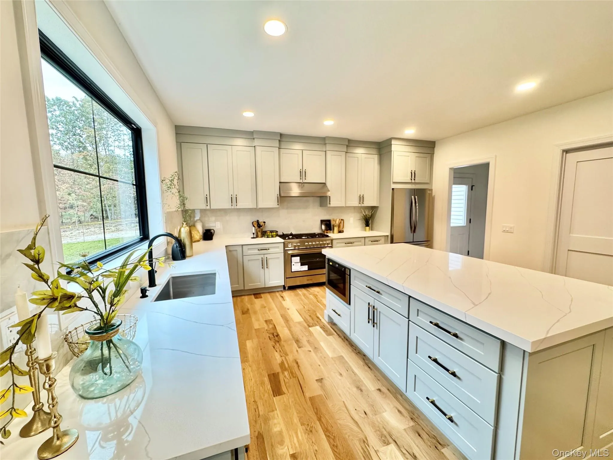 Kitchen with light stone counters, stainless steel appliances, tasteful backsplash, a center island, and recessed lighting Kitchen with light stone counters, stainless steel appliances, tasteful backsplash, a center island, and recessed lighting