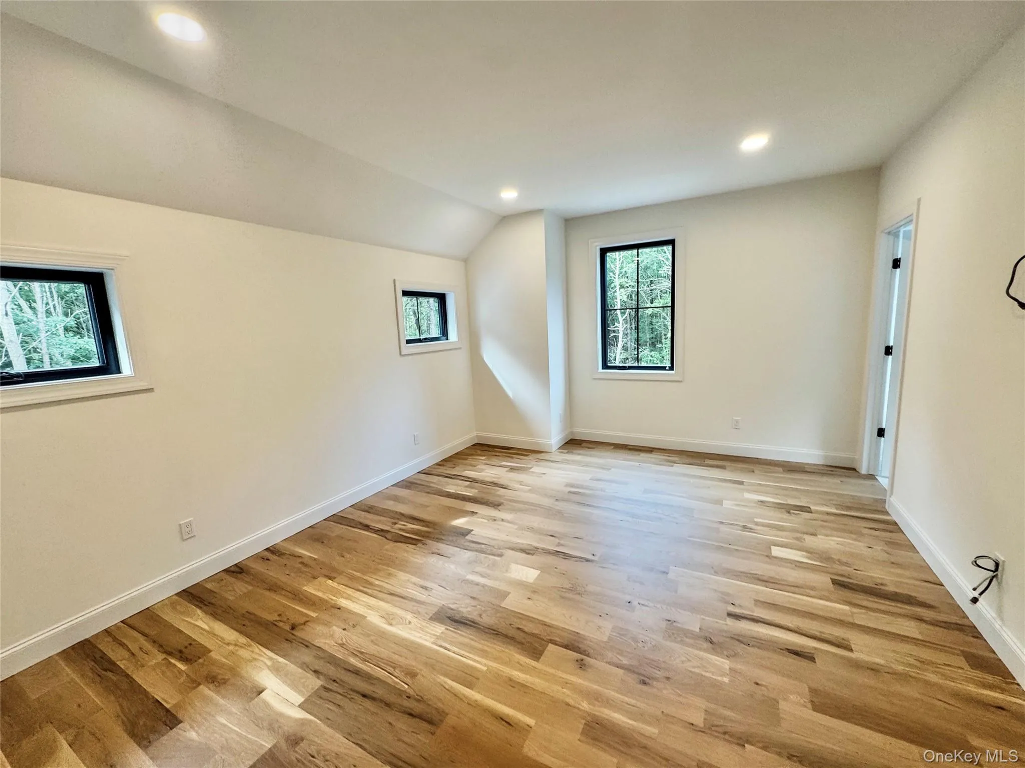 Unfurnished room featuring recessed lighting, light wood-style flooring, and lofted ceiling Unfurnished room featuring recessed lighting, light wood-style flooring, and lofted ceiling