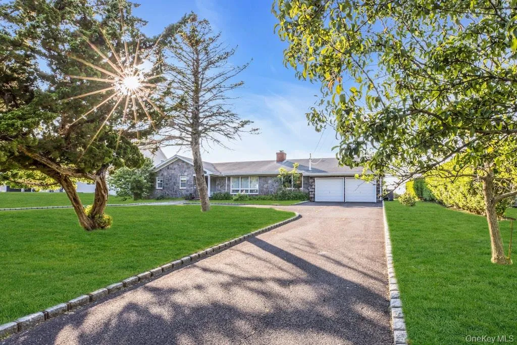 Ranch-style house with asphalt driveway, a chimney, a front yard, and stone siding Ranch-style house with asphalt driveway, a chimney, a front yard, and stone siding