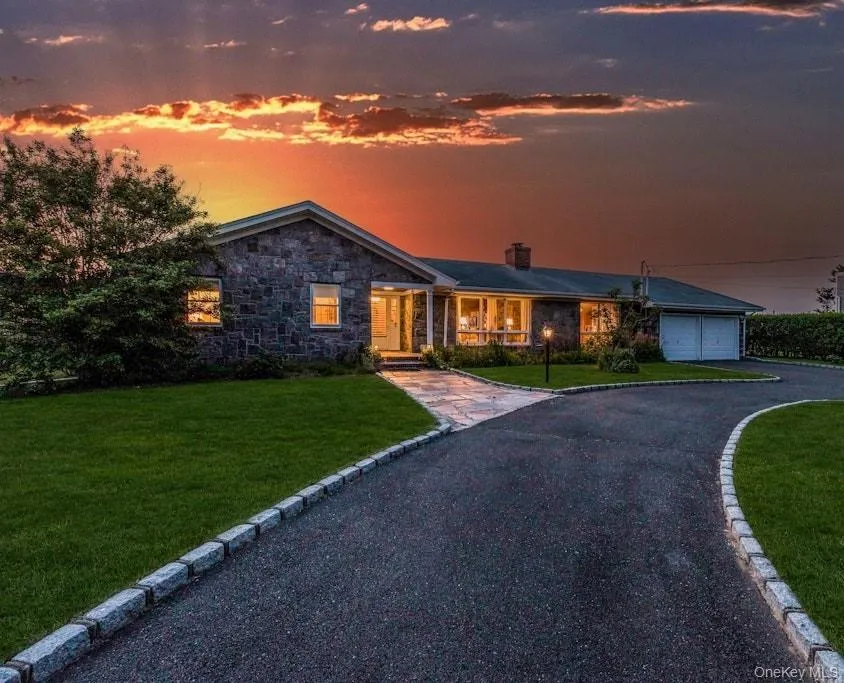 View of front of house featuring driveway, a yard, a garage, a chimney, and stone siding View of front of house featuring driveway, a yard, a garage, a chimney, and stone siding