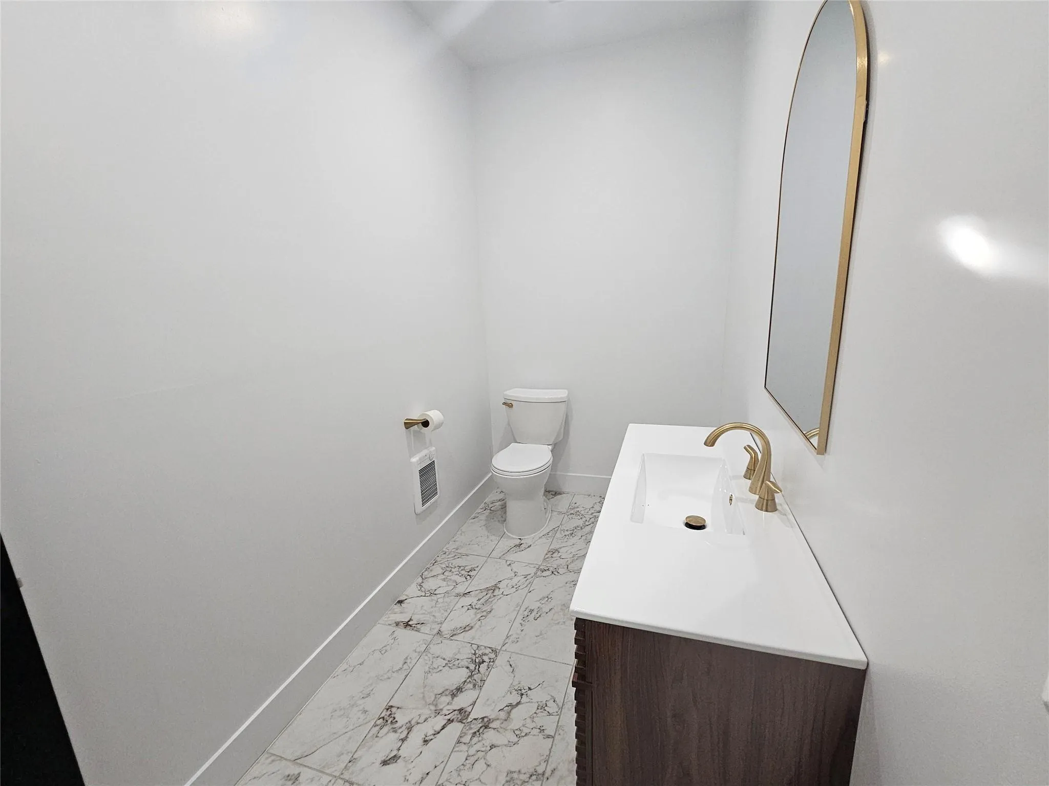 Half bath with marble look tile flooring, toilet, baseboards, and vanity Half bath with marble look tile flooring, toilet, baseboards, and vanity