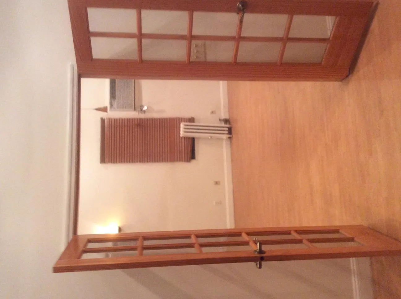 Hallway with french doors, radiator, light wood-type flooring, and baseboards Hallway with french doors, radiator, light wood-type flooring, and baseboards