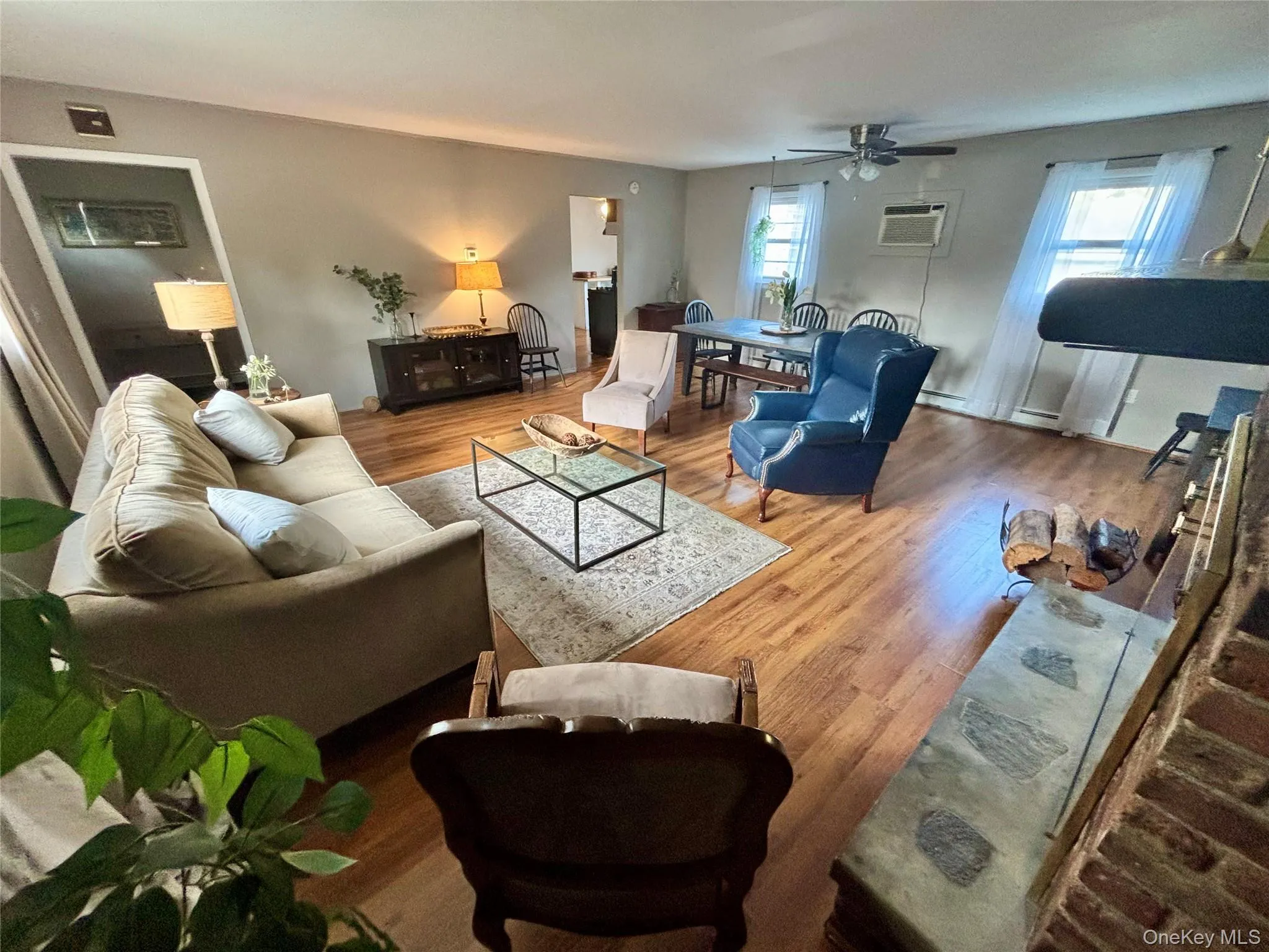 Living area with ceiling fan, an AC wall unit, and wood finished floors Living area with ceiling fan, an AC wall unit, and wood finished floors