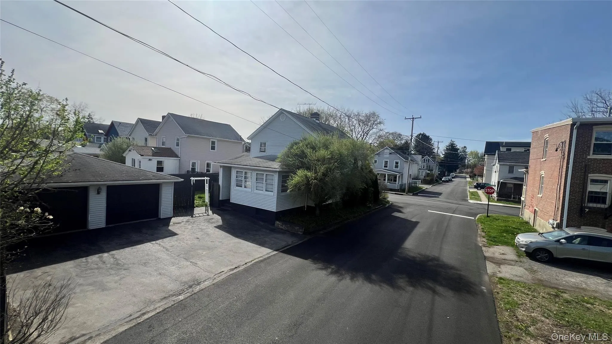 View of asphalt street featuring a residential view and traffic signs View of asphalt street featuring a residential view and traffic signs