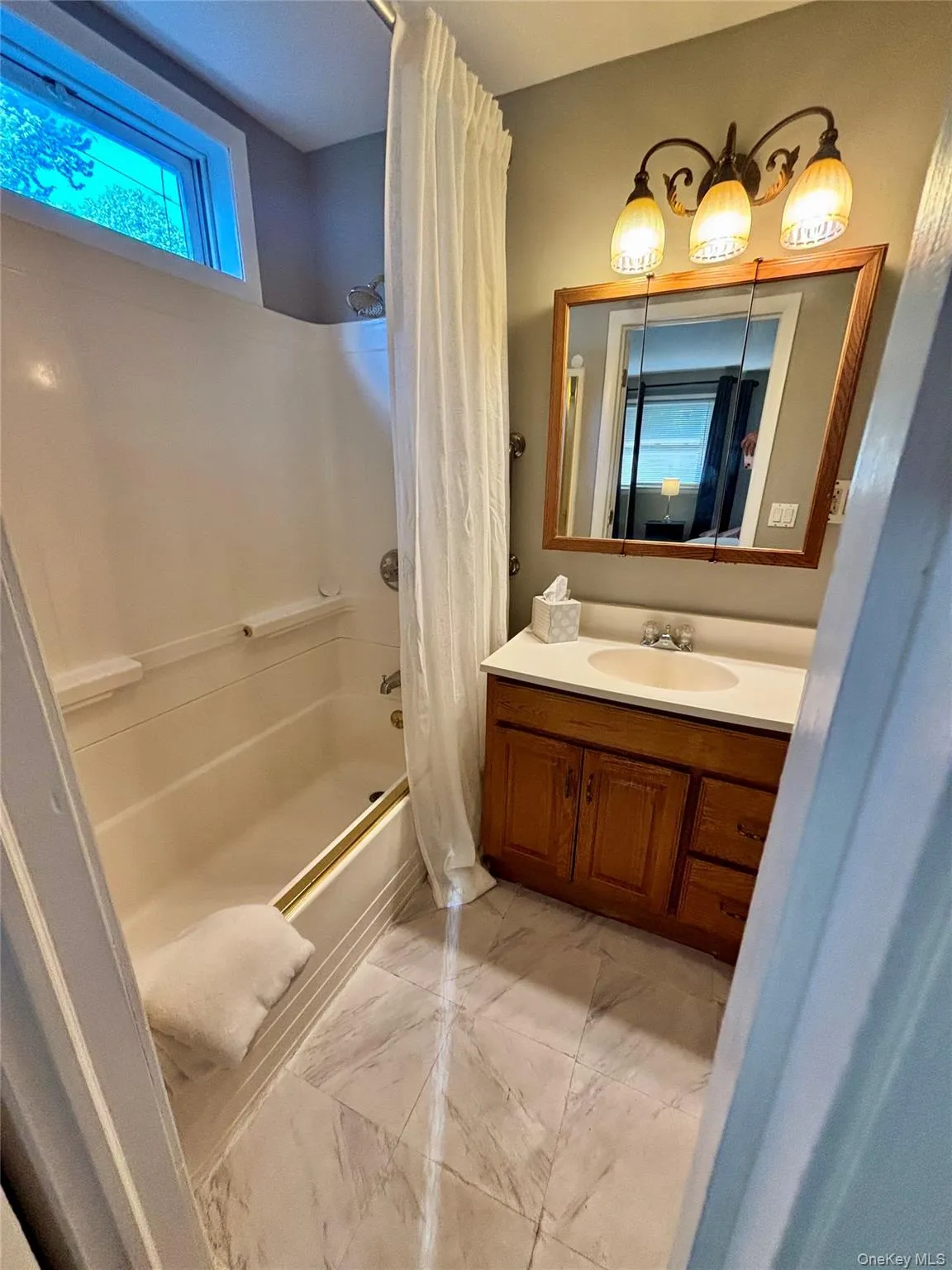 Bathroom featuring shower / bath combination with curtain, marble finish flooring, and vanity Bathroom featuring shower / bath combination with curtain, marble finish flooring, and vanity