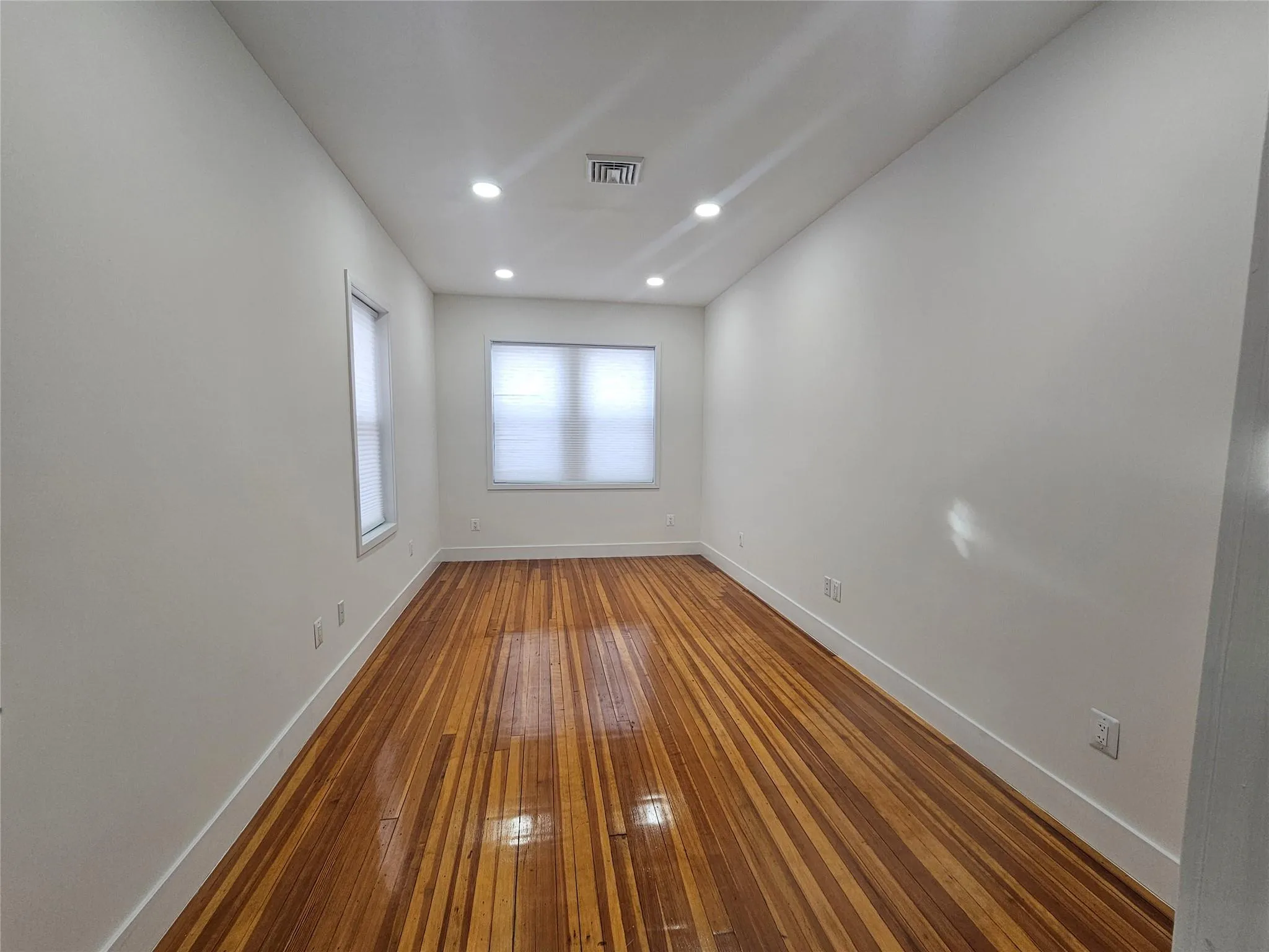 Unfurnished room featuring baseboards, wood-type flooring, and recessed lighting Unfurnished room featuring baseboards, wood-type flooring, and recessed lighting