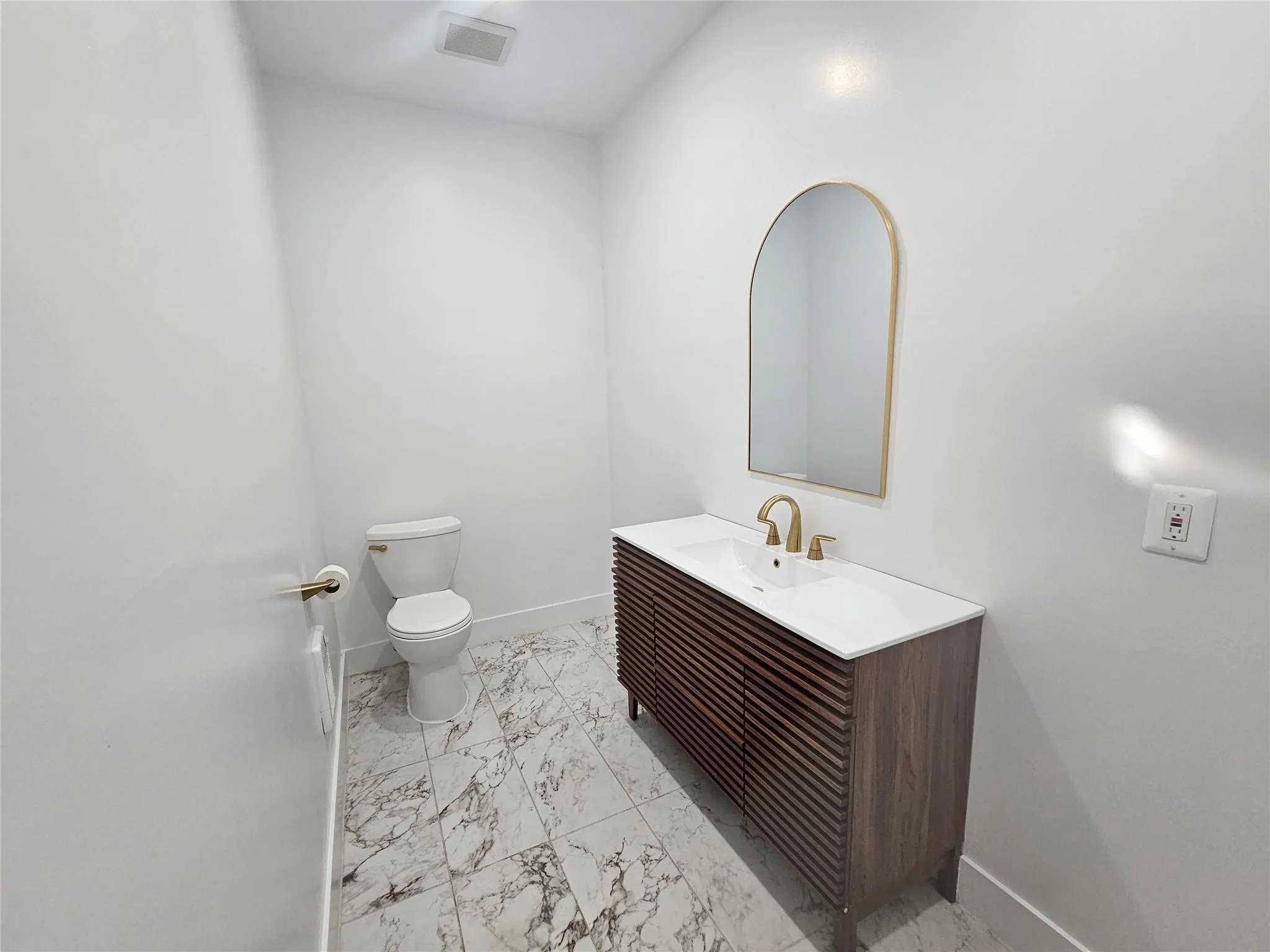 Half bathroom featuring marble finish floors, toilet, baseboards, and vanity Half bathroom featuring marble finish floors, toilet, baseboards, and vanity