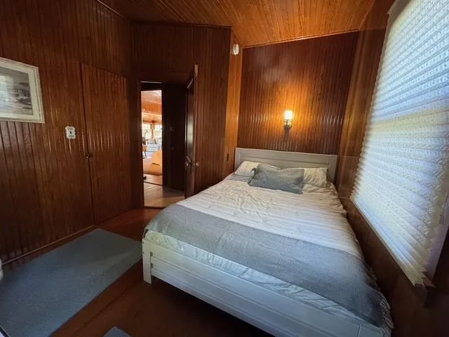 Bedroom with wooden walls, wood finished floors, and wood ceiling Bedroom with wooden walls, wood finished floors, and wood ceiling