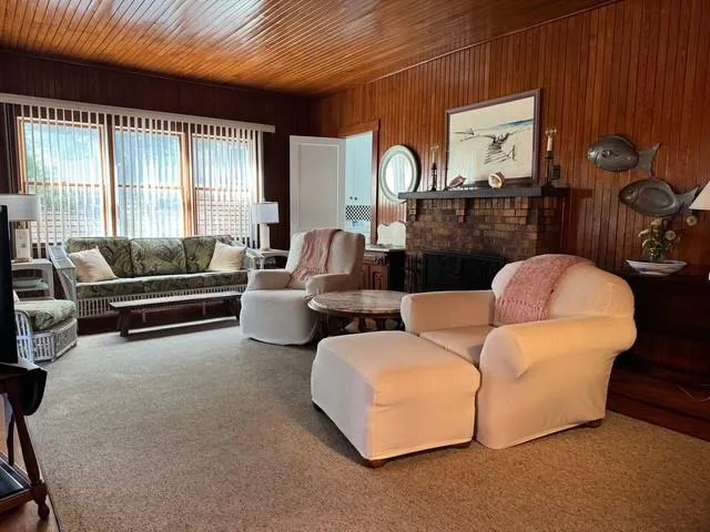 Carpeted living area with wooden walls, a fireplace, and wood ceiling Carpeted living area with wooden walls, a fireplace, and wood ceiling