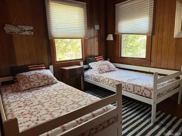 Bedroom featuring multiple windows and wooden walls Bedroom featuring multiple windows and wooden walls