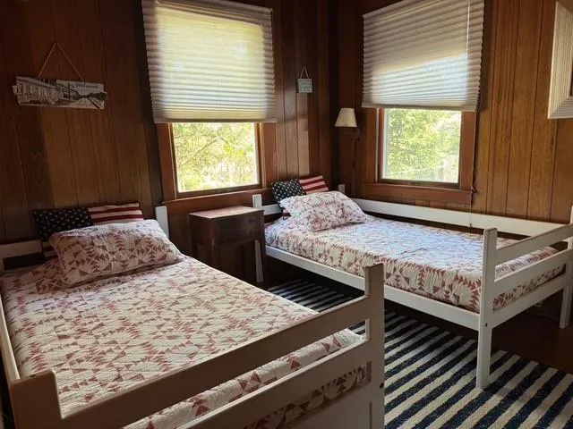 Bedroom featuring multiple windows and wooden walls Bedroom featuring multiple windows and wooden walls