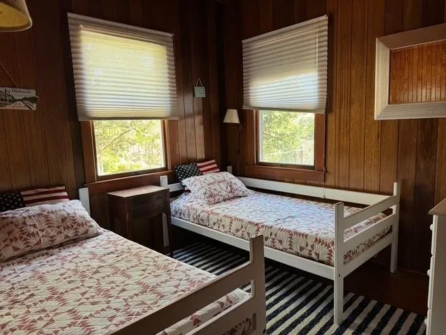 Bedroom featuring wood walls and multiple windows Bedroom featuring wood walls and multiple windows