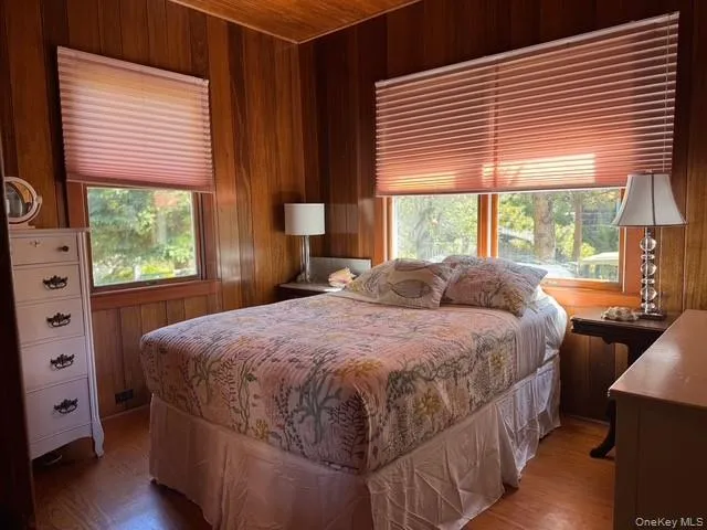 Bedroom featuring wooden walls, wood finished floors, and wooden ceiling Bedroom featuring wooden walls, wood finished floors, and wooden ceiling