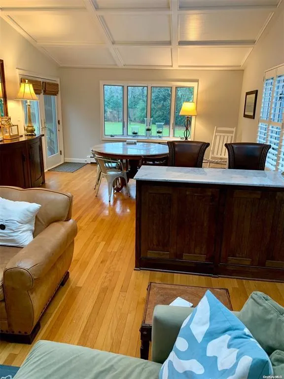 Living room featuring plenty of natural light, light wood finished floors, vaulted ceiling, and baseboards Living room featuring plenty of natural light, light wood finished floors, vaulted ceiling, and baseboards