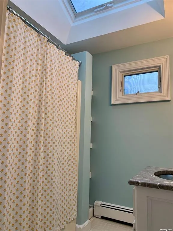 Bathroom featuring a baseboard radiator, curtained shower, baseboards, and vanity Bathroom featuring a baseboard radiator, curtained shower, baseboards, and vanity