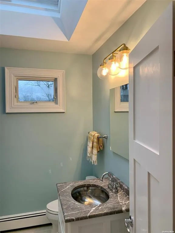 Full bath featuring a baseboard radiator, toilet, and vanity Full bath featuring a baseboard radiator, toilet, and vanity