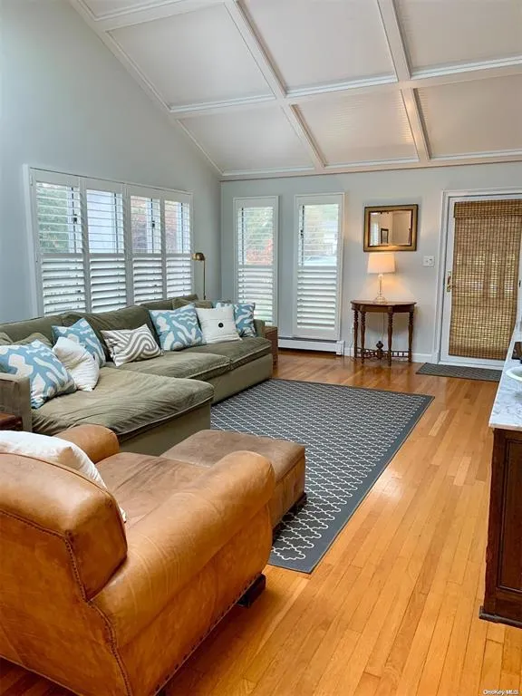 Living room featuring coffered ceiling, light wood-style floors, and baseboards Living room featuring coffered ceiling, light wood-style floors, and baseboards