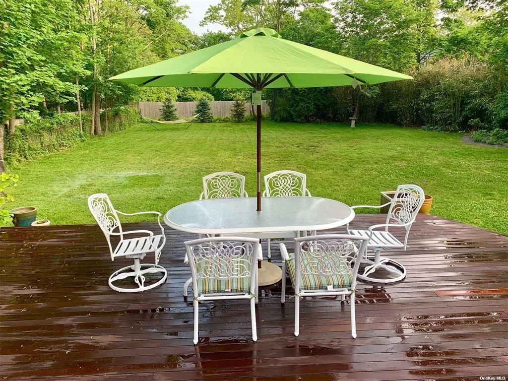 Wooden terrace featuring outdoor dining area and a lawn Wooden terrace featuring outdoor dining area and a lawn