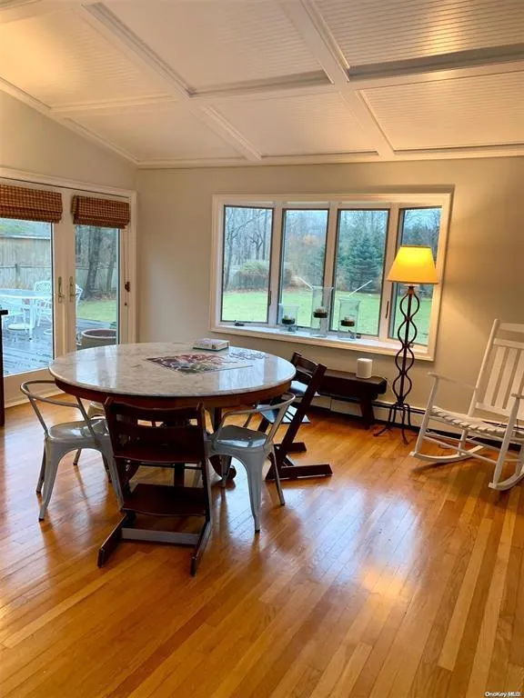 Dining room with coffered ceiling, light wood-type flooring, beam ceiling, and baseboard heating Dining room with coffered ceiling, light wood-type flooring, beam ceiling, and baseboard heating