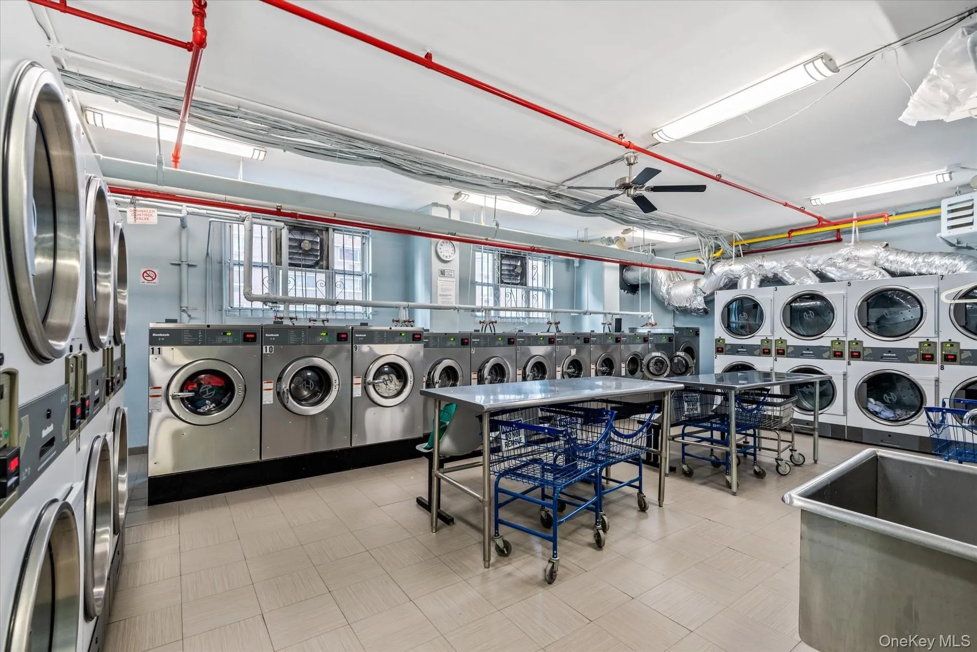Shared laundry featuring stacked washing machine and dryer, washing machine and clothes dryer, tile patterned floors, and ceiling fan Shared laundry featuring stacked washing machine and dryer, washing machine and clothes dryer, tile patterned floors, and ceiling fan