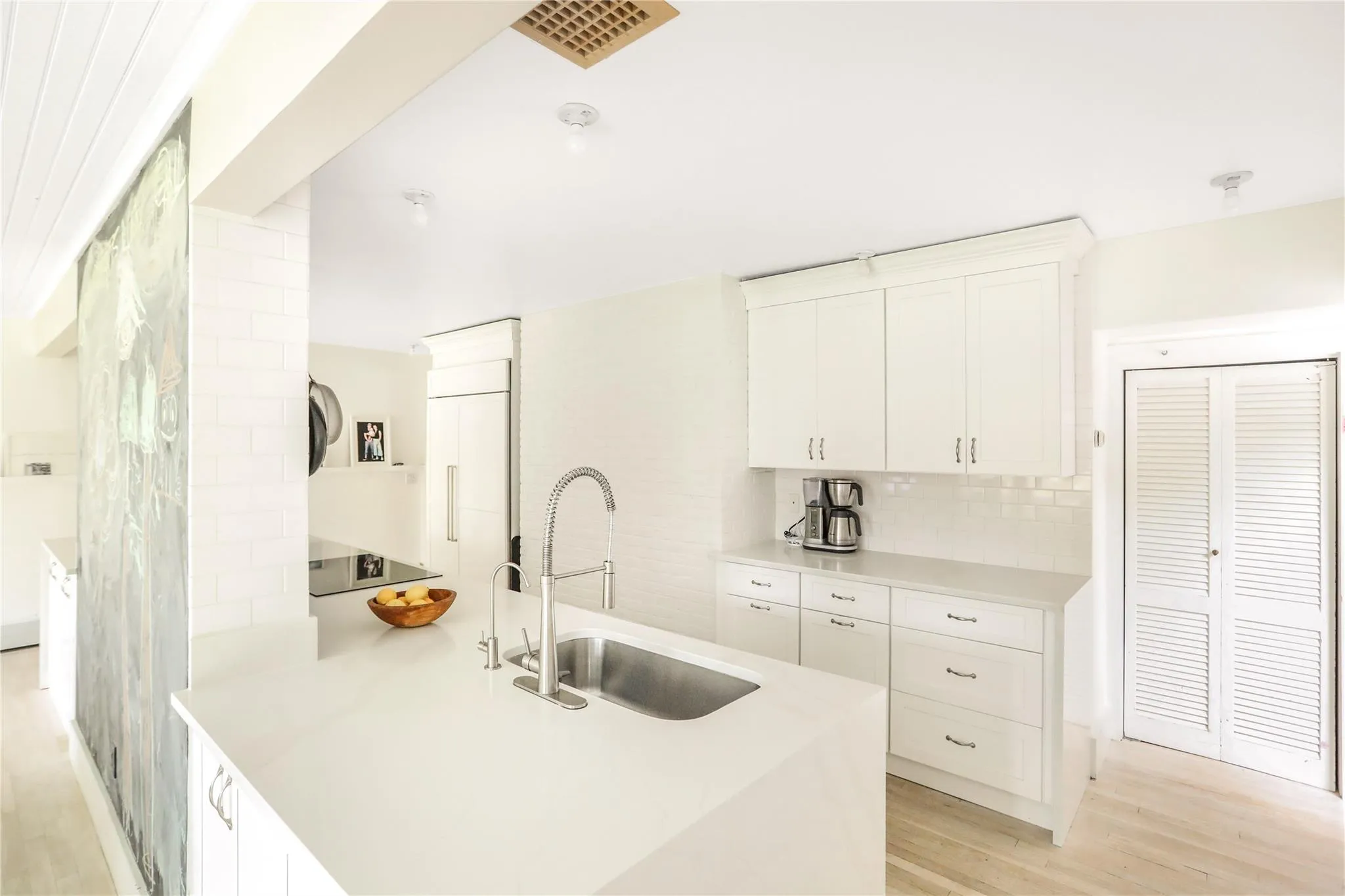 Kitchen with a sink, decorative backsplash, light wood-type flooring, white cabinets, and light countertops Kitchen with a sink, decorative backsplash, light wood-type flooring, white cabinets, and light countertops